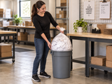 Garbage Bags - 30" x 38" - Clear - Strong - 20-30 gal - 200/Case closed clear bag being removed from an opaque commercial waste bin in a packing area