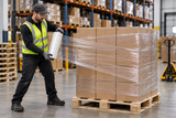 Worker applying clear hand stretch wrap to a palletized load in a warehouse